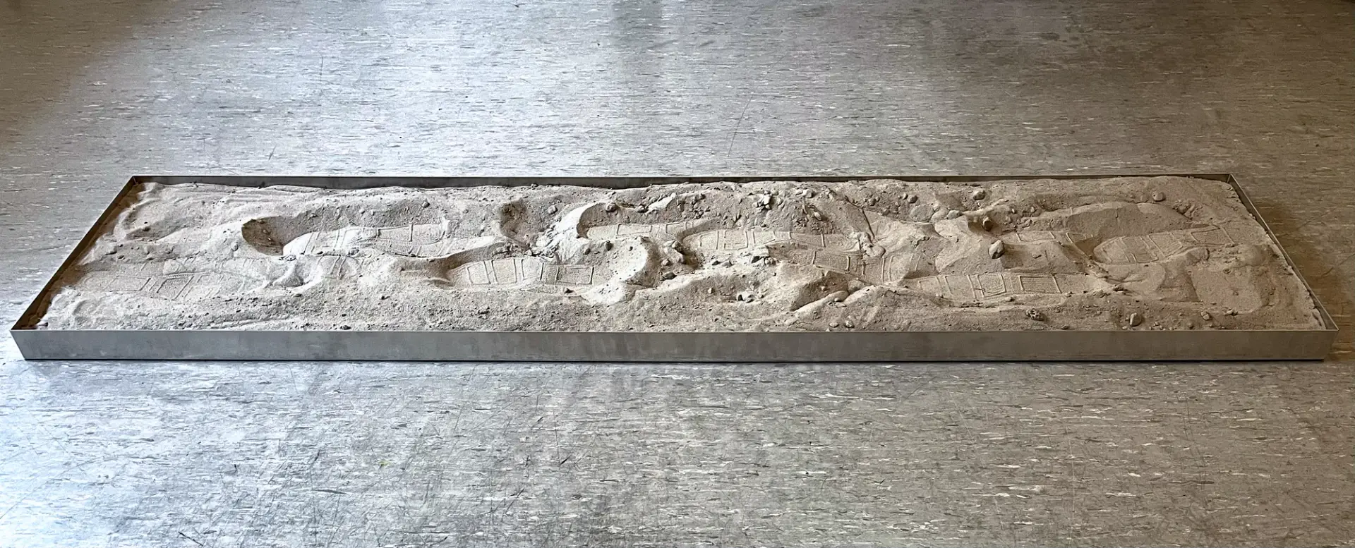 path0165, aluminium box filled with sand showing footprints and pressure marks.